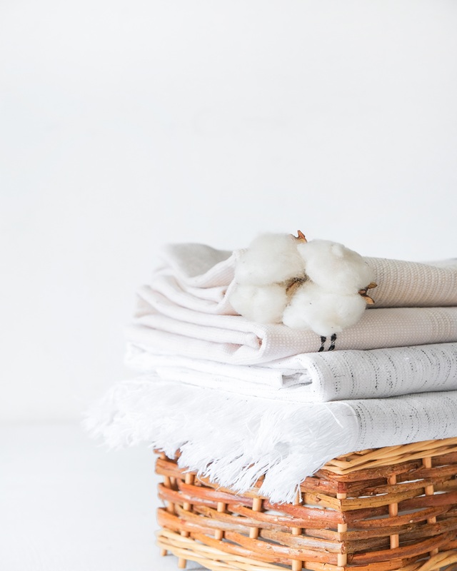 Cotton branch with pile of folded bed sheets and blankets.Organic lifestyle and skin care products